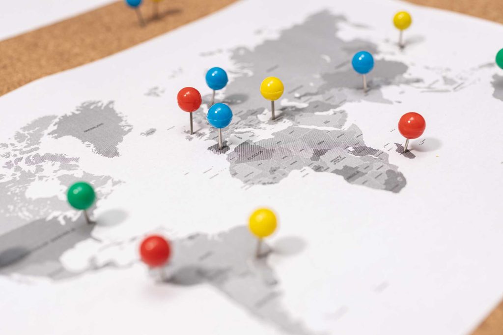 Map with colorful push pins marking various locations across North America, Europe, and Africa on a white and gray world map.
